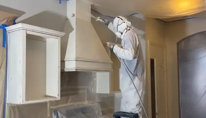 Schneider painter in a full spray suit finishing cabinet boxes