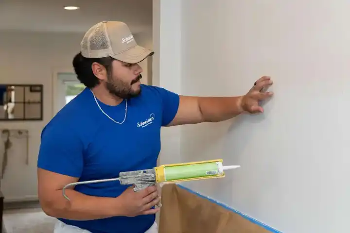 Schneider painter caulking a wall seam before painting