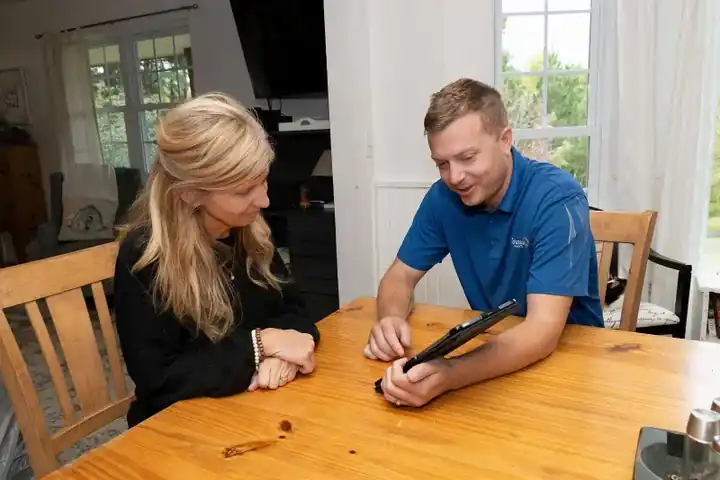 A Schneider Painting team member going over project plans with a homeowner at a table