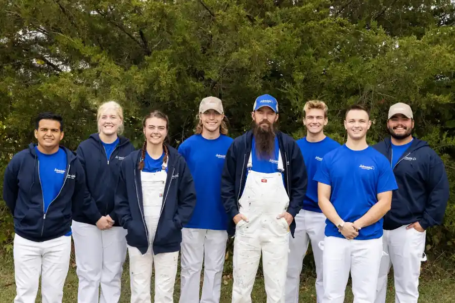 The Schneider Painting crew in blue shirts, navy jackets and white painter's whites