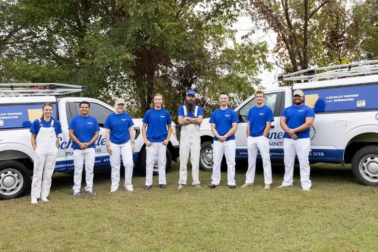 The Schneider Painting crew lined up between two white branded vans