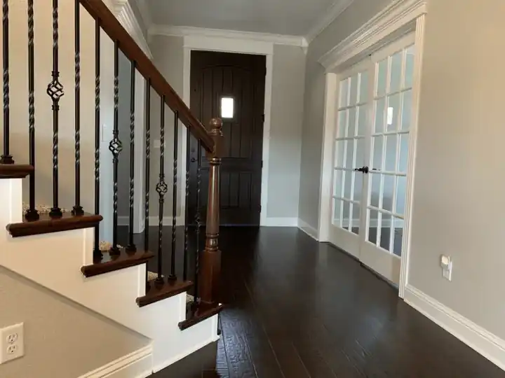 Painted staircase with iron balusters and a dark floor